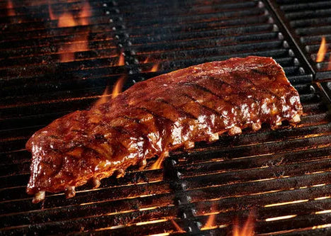 Grilled ribs on a barbecue grill with flames