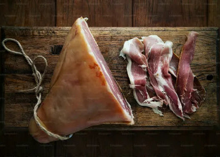 Raw cured meat on a wooden cutting board with a dark background