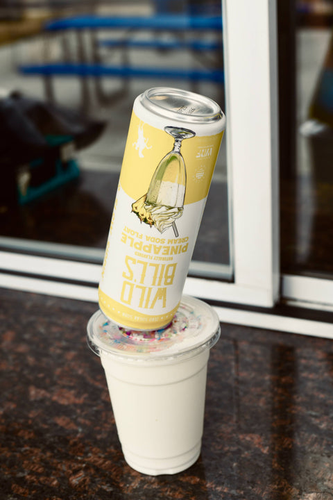 Can of beer with a yellow label on a white cup against a blurred indoor background
