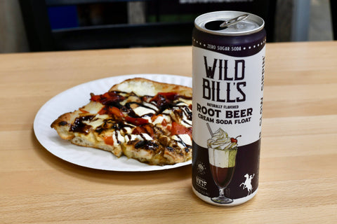 Can of Wild Bill's Root Beer next to a slice of pizza on a table