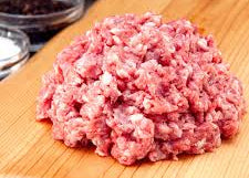Raw ground meat on a wooden cutting board with spices in the background