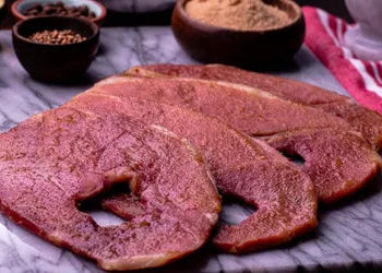 Raw meat on a marble surface with spices in the background