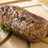 Grilled meatloaf on a wooden cutting board with herbs