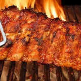 Grilled ribs on a barbecue with flames in the background
