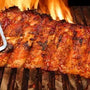 Grilled ribs on a barbecue with flames in the background