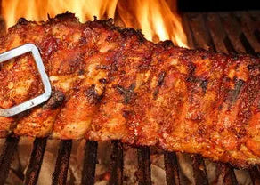 Grilled ribs on a barbecue with flames in the background