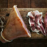 Raw cured meat on a wooden cutting board with a dark background