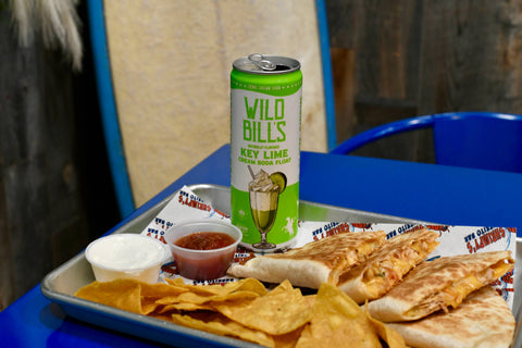 Can of Wild Bill's Key Lime soda on a tray with nachos, salsa, and tortilla chips.